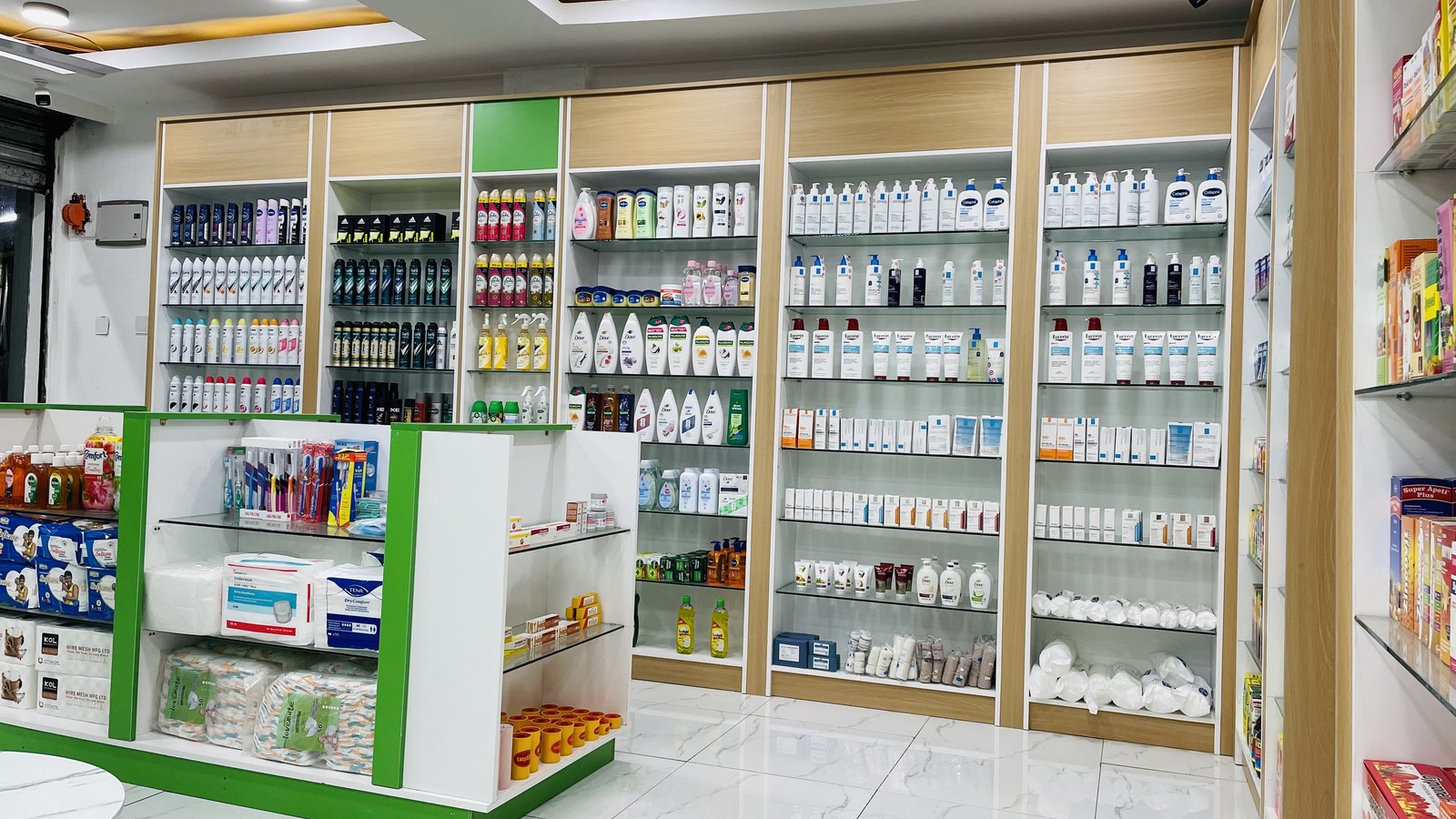 Inside Unihealth Pharmacy, with green display islands and shelves of skincare and everyday care products.